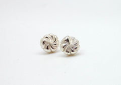 Two silver earrings with spiral designs are shown against a white background.