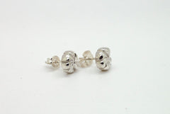 A pair of silver earrings with spiral designs on the back rests on a white surface.