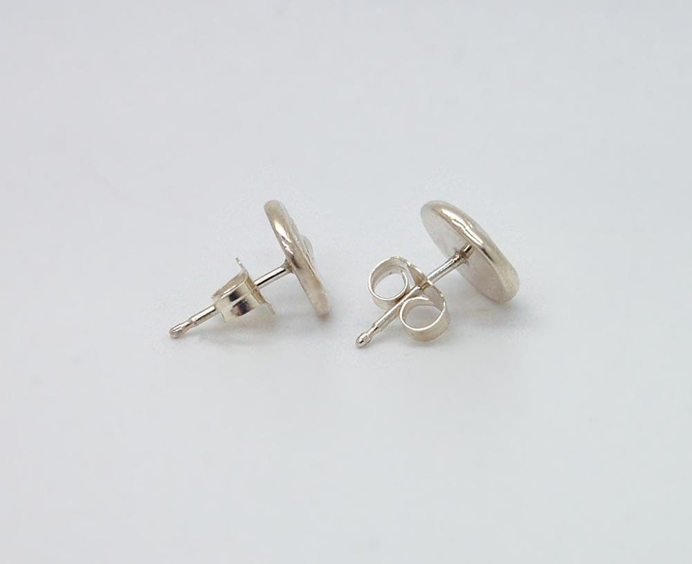 A pair of silver earrings with round posts and circular backs, placed on a white background.