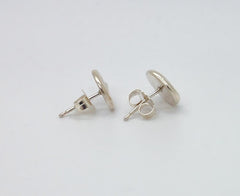 A pair of silver earrings with round posts and circular backs, placed on a white background.